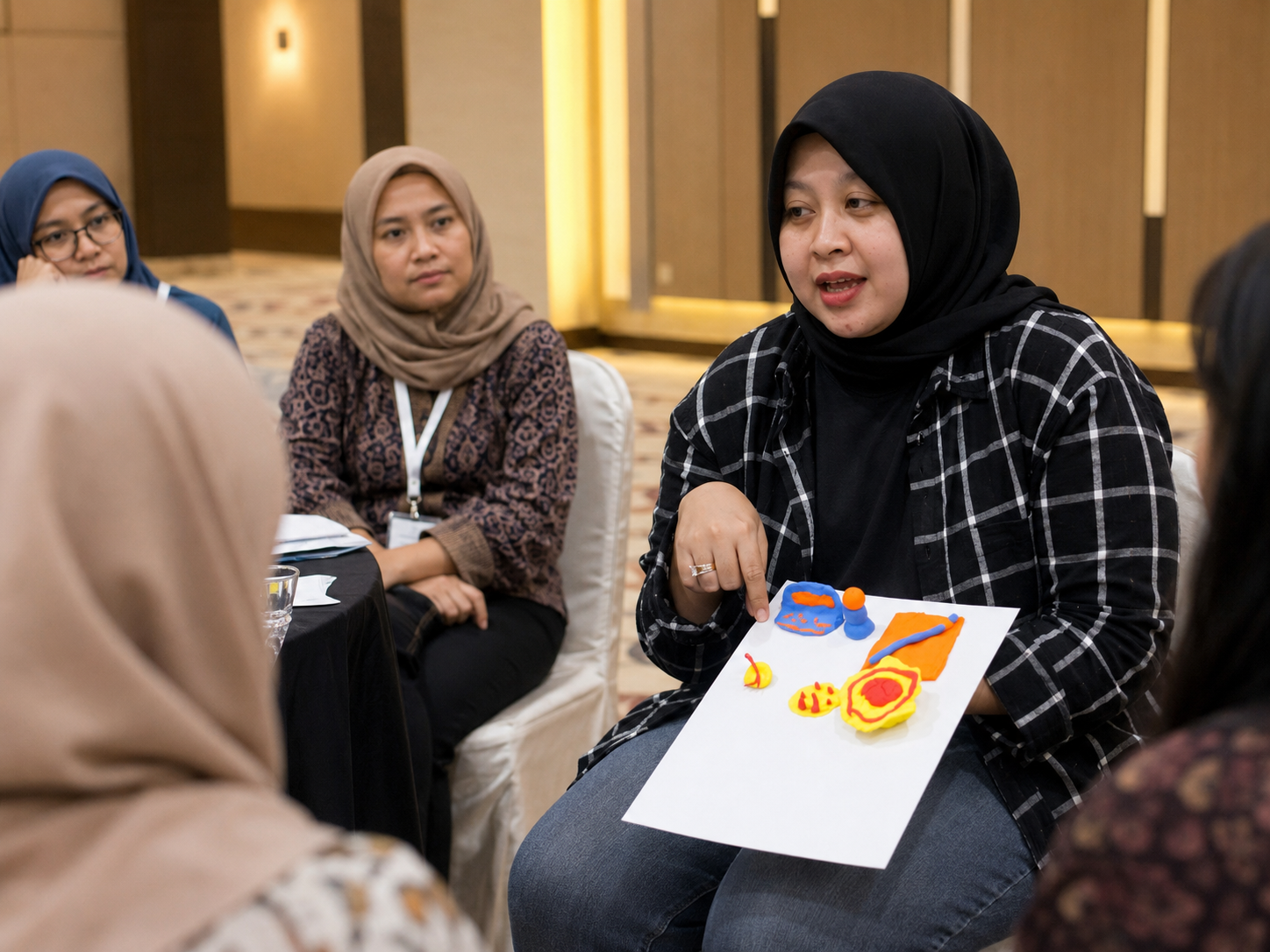 Sekelompok karyawan lintas generasi melakukan simulasi taktil experiential learning menggunakan media kreatif di ruang rapat modern.